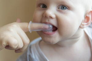 Mom Brushes Baby's Teeth With A Brush That Fits On Her Finger